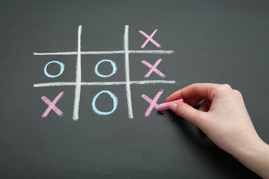 Woman playing tic tac toe on chalkboard, closeup