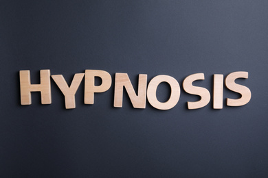 Word HYPNOSIS made with wooden letters on black background, flat lay