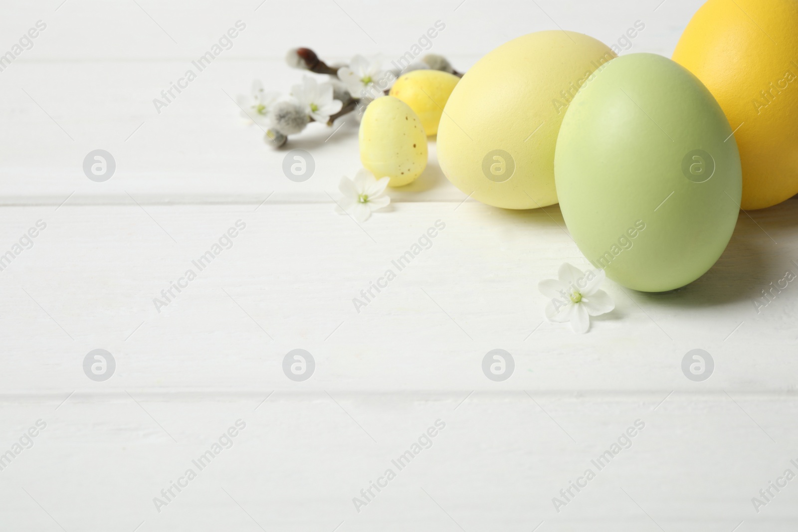 Photo of Colorful Easter eggs on white wooden table. Space for text