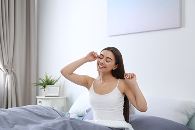 Photo of Young woman stretching at home in morning. Bedtime