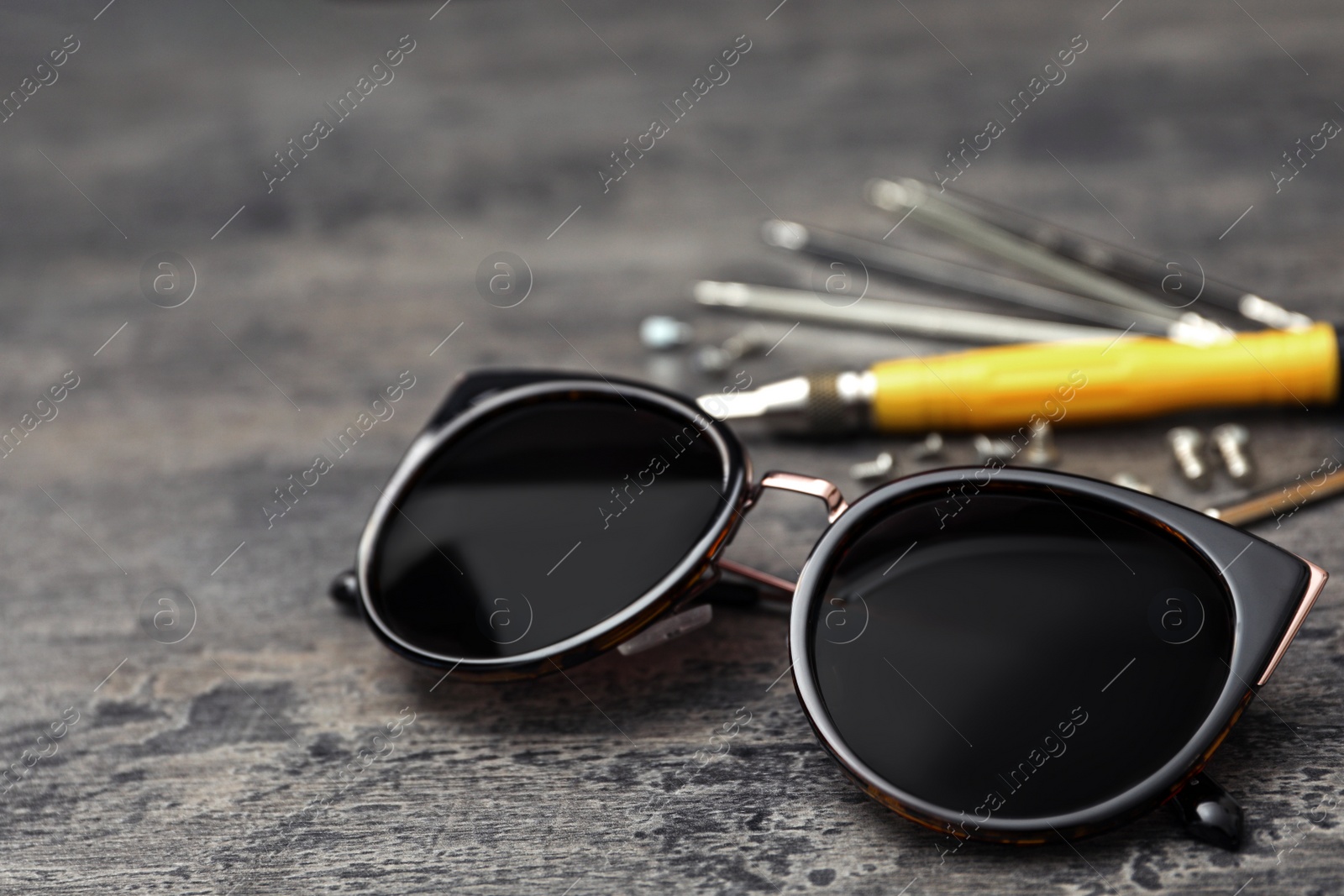 Photo of Stylish female sunglasses and fixing tools on grey table