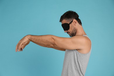 Photo of Man with eye mask in sleepwalking state on light blue background