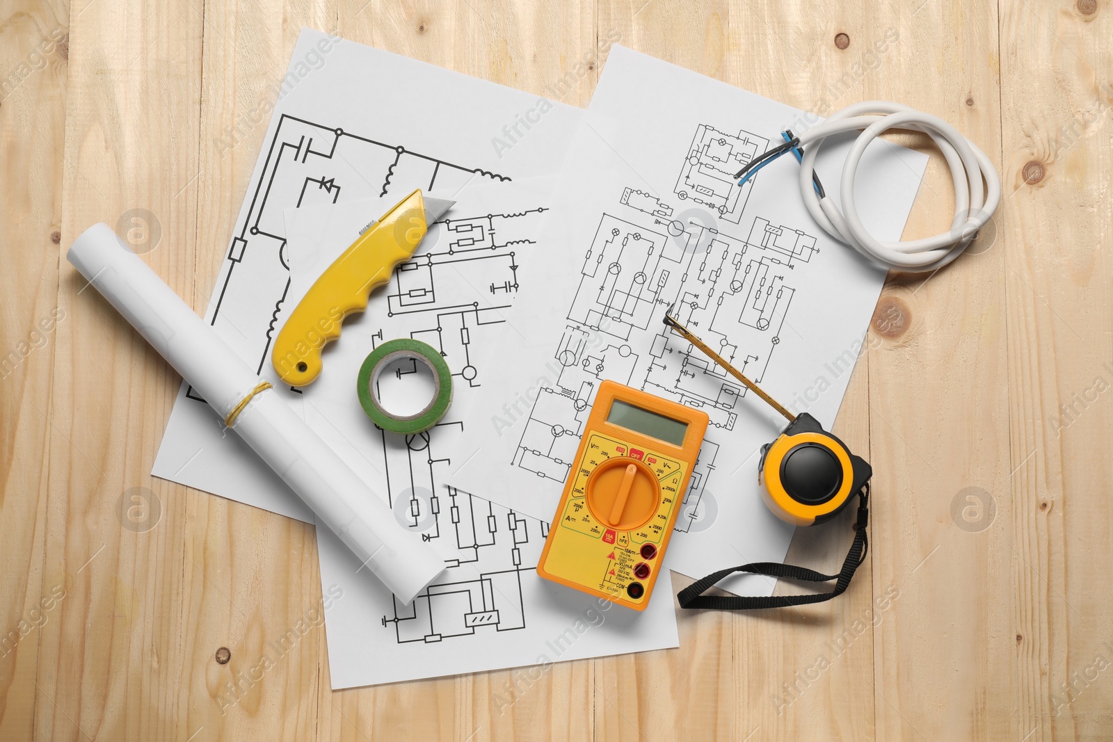 Photo of Wiring diagrams, wires and digital multimeter on wooden table, flat lay