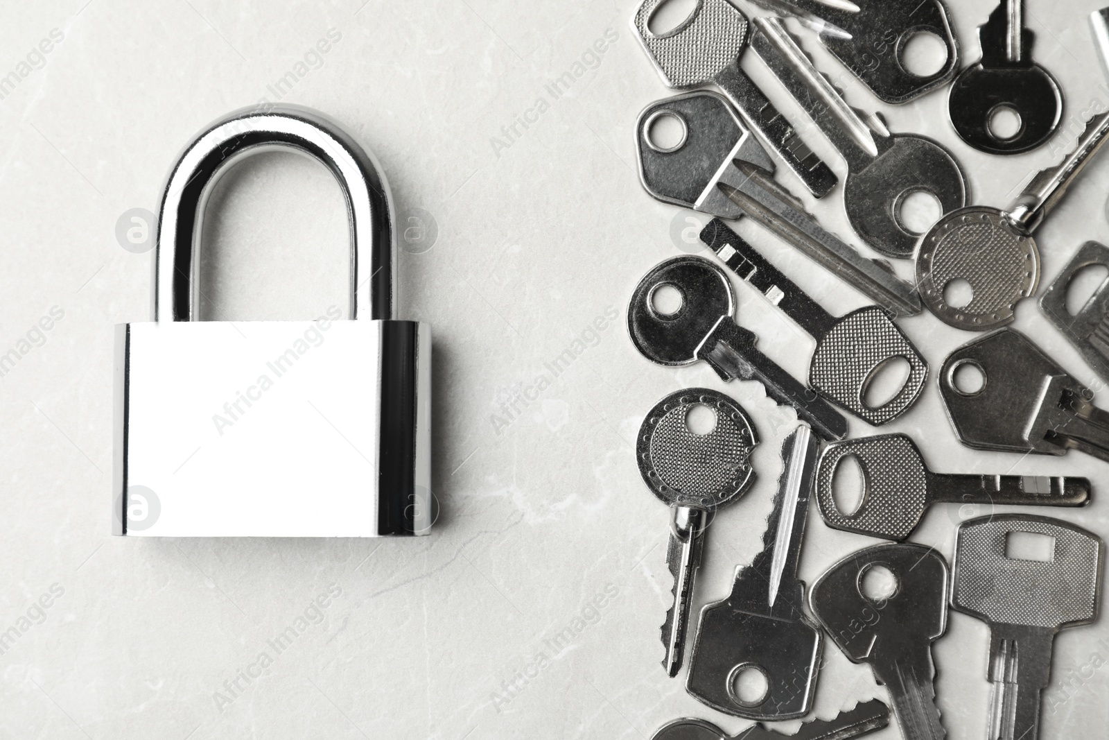 Photo of Steel padlock and keys on marble background, flat lay. Safety concept