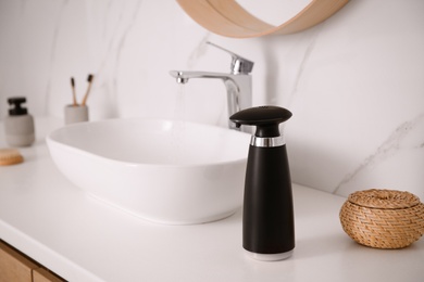 Modern automatic soap dispenser on countertop in bathroom