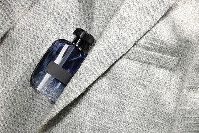 Luxury men's perfume in bottle on grey jacket, top view. Space for text