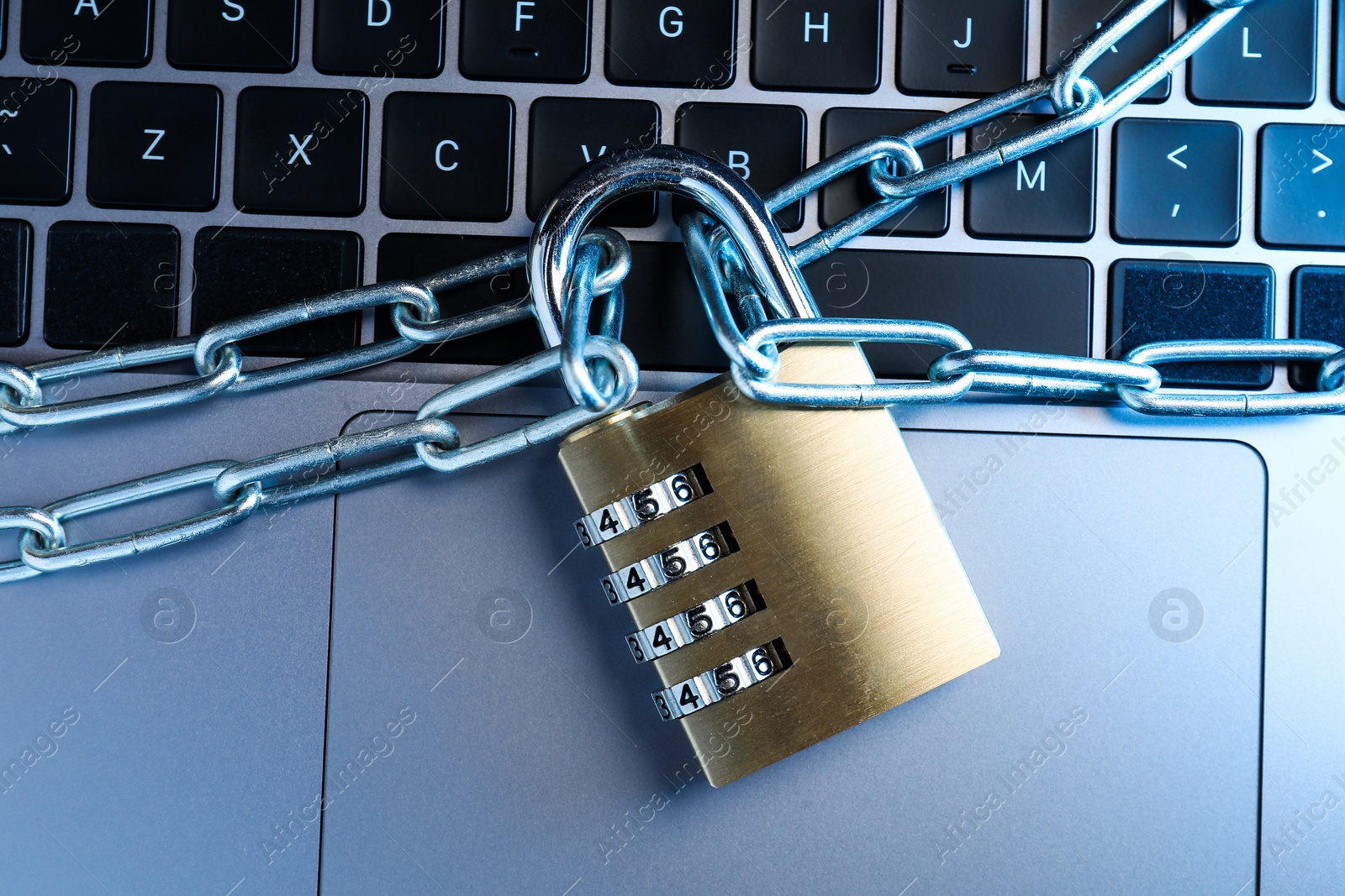 Photo of Cyber security. Metal combination padlock with chain on laptop, top view