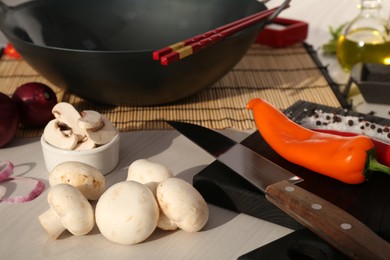 Photo of Wok, chopsticks and different products on white wooden table, closeup