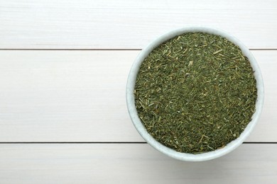 Dried dill in bowl on white wooden table, top view. Space for text