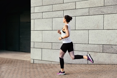 Photo of Beautiful sporty young woman running on street