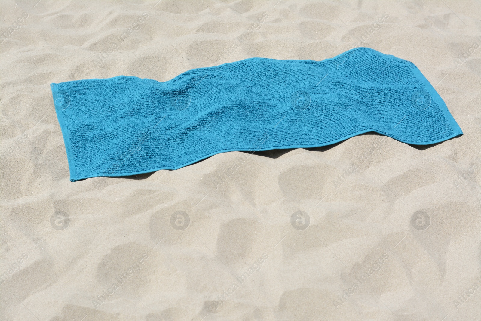 Photo of Soft blue towel on sandy beach, space for text