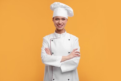 Photo of Happy chef in uniform on orange background