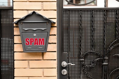 Mailbox with word Spam on brick wall near house