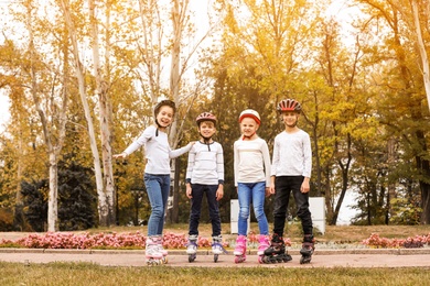 Photo of Happy children wearing roller skates in autumn park
