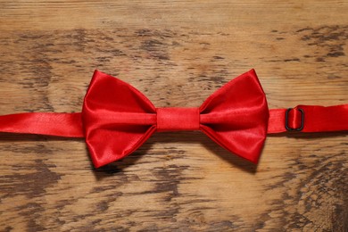 Photo of Stylish red bow tie on wooden table, top view