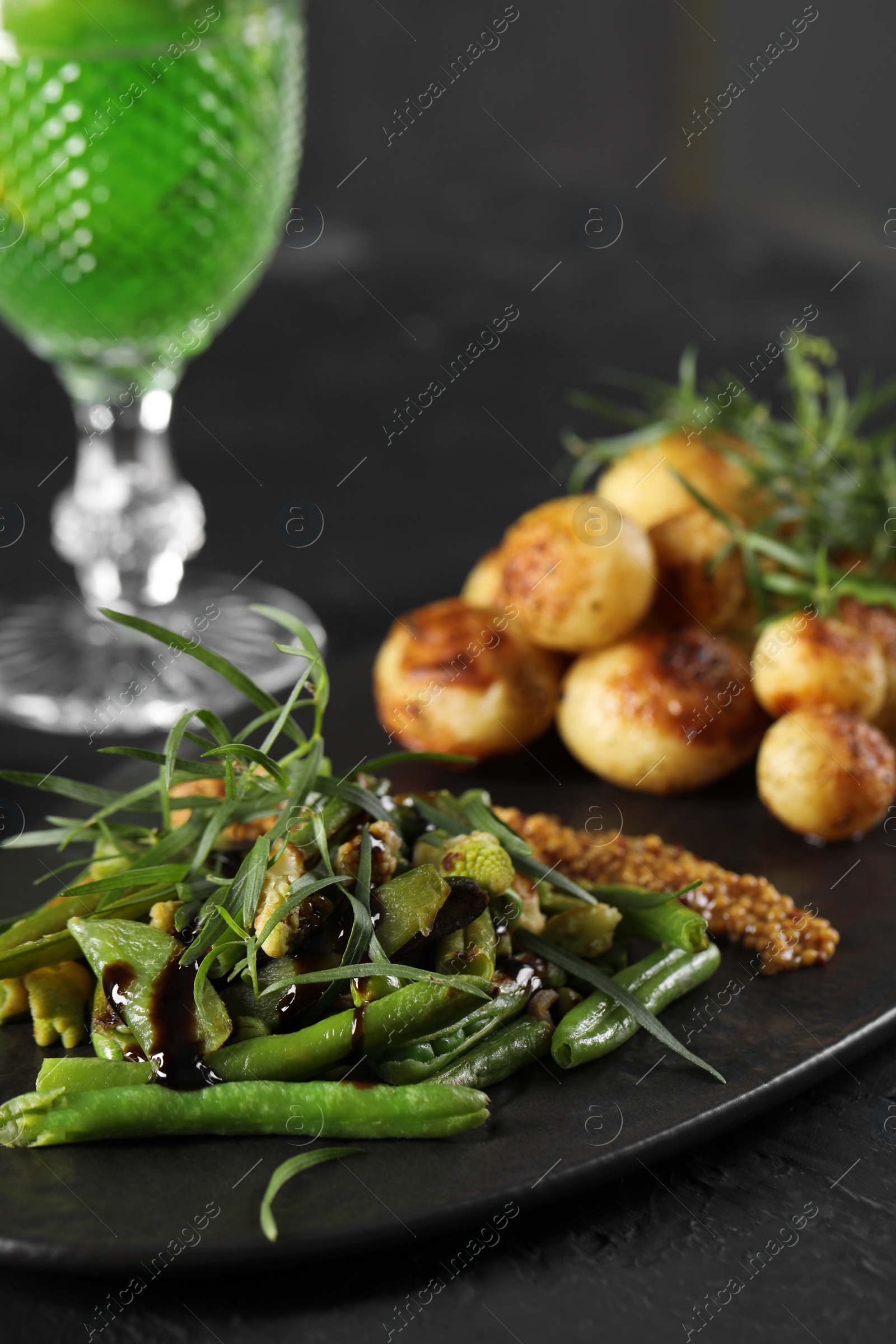 Photo of Delicious salad with tarragon, mustard and grilled potatoes on black table