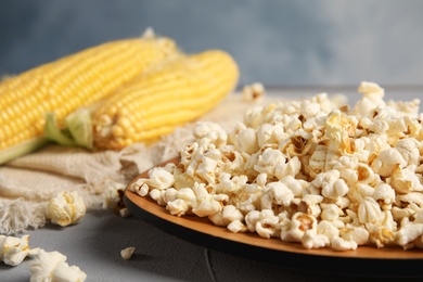 Plate with delicious popcorn on table, closeup