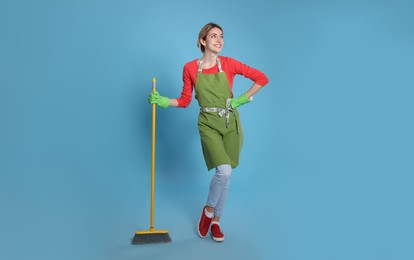 Photo of Young housewife with broom on light blue background