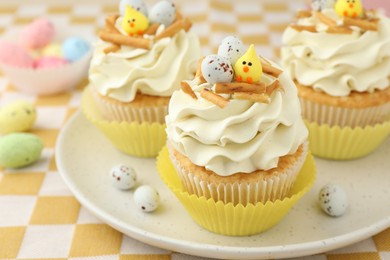 Photo of Tasty Easter cupcakes with vanilla cream on table, closeup