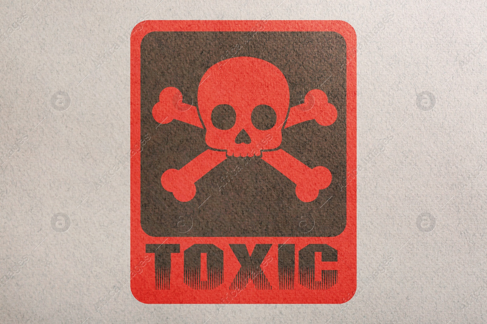 Image of Hazard warning sign (skull-and-crossbones symbol and word TOXIC) on paper, top view