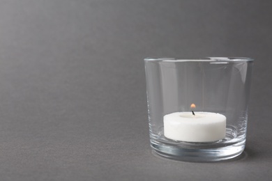 Photo of Candle in glass holder on grey background. Space for text