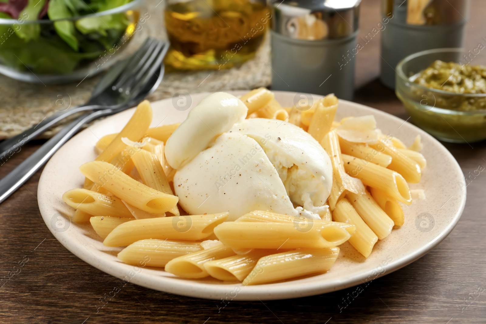 Photo of Plate of delicious pasta with burrata on wooden table