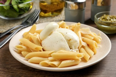 Plate of delicious pasta with burrata on wooden table