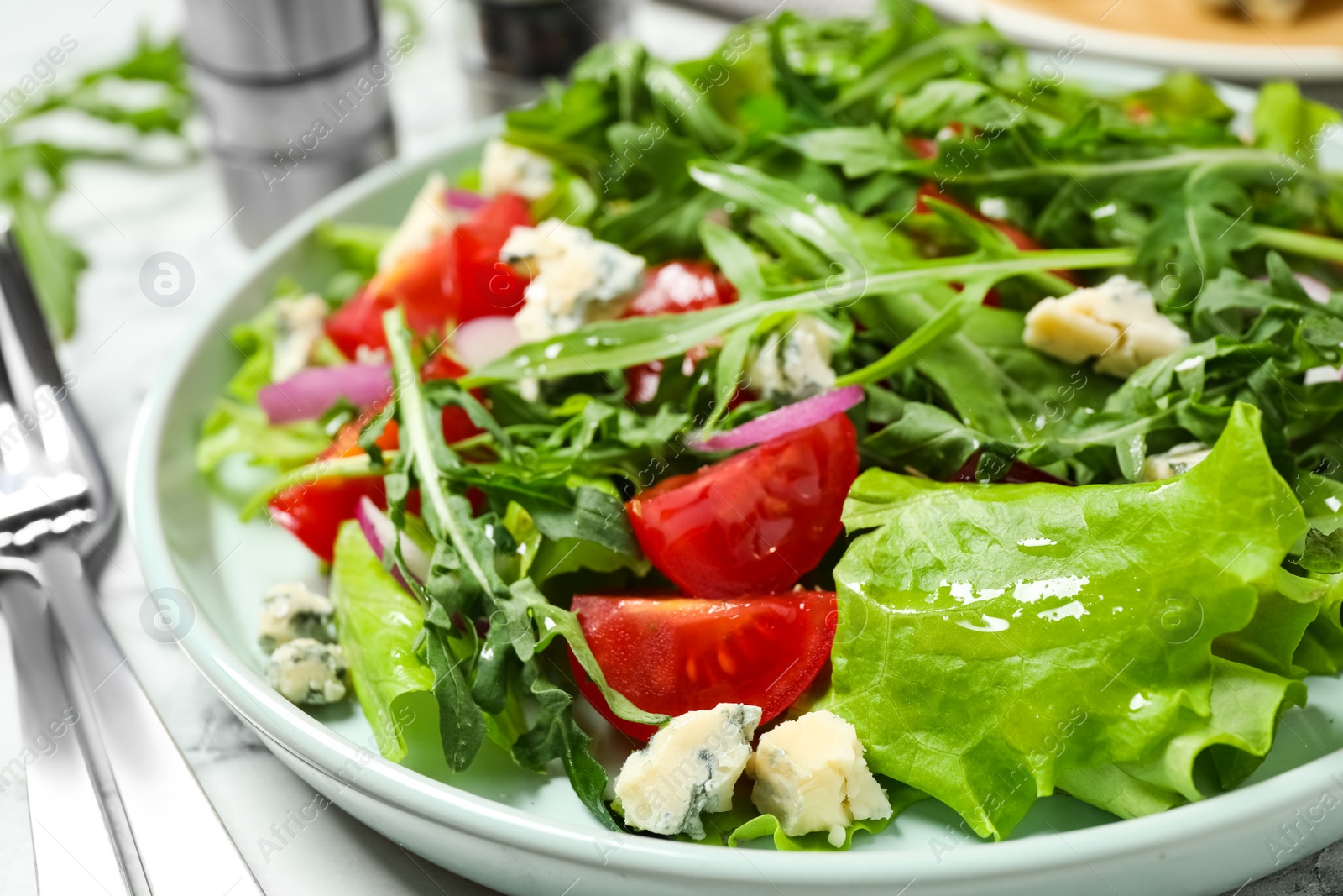 Photo of Delicious salad with arugula and tomatoes on white table, closeup