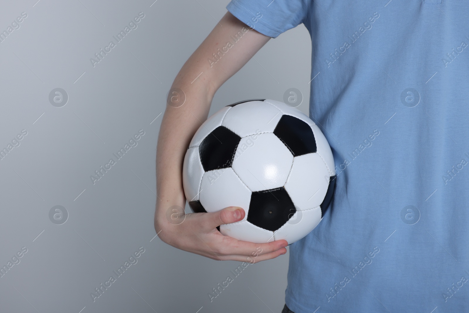 Photo of Boy with soccer ball on light grey background, closeup. Space for text