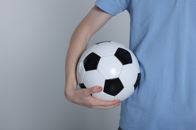 Photo of Boy with soccer ball on light grey background, closeup. Space for text