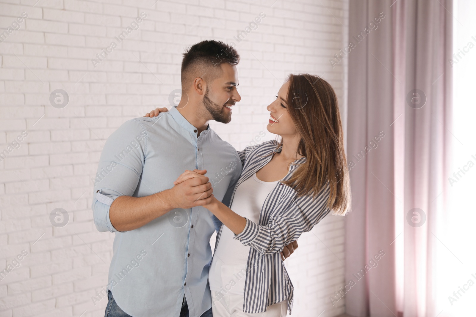 Photo of Lovely young couple dancing together at home