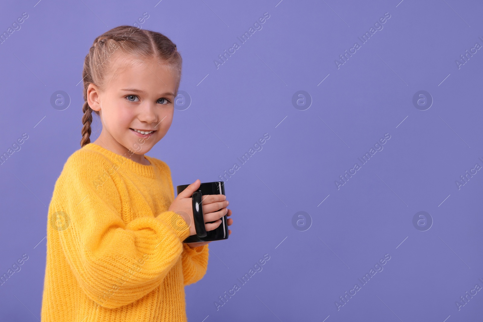 Photo of Happy girl with black ceramic mug on violet background, space for text