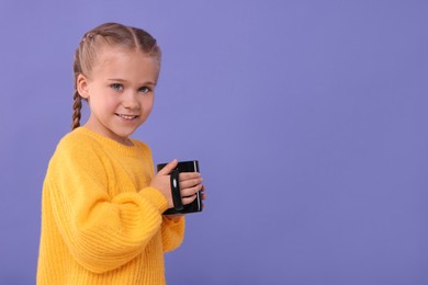 Happy girl with black ceramic mug on violet background, space for text