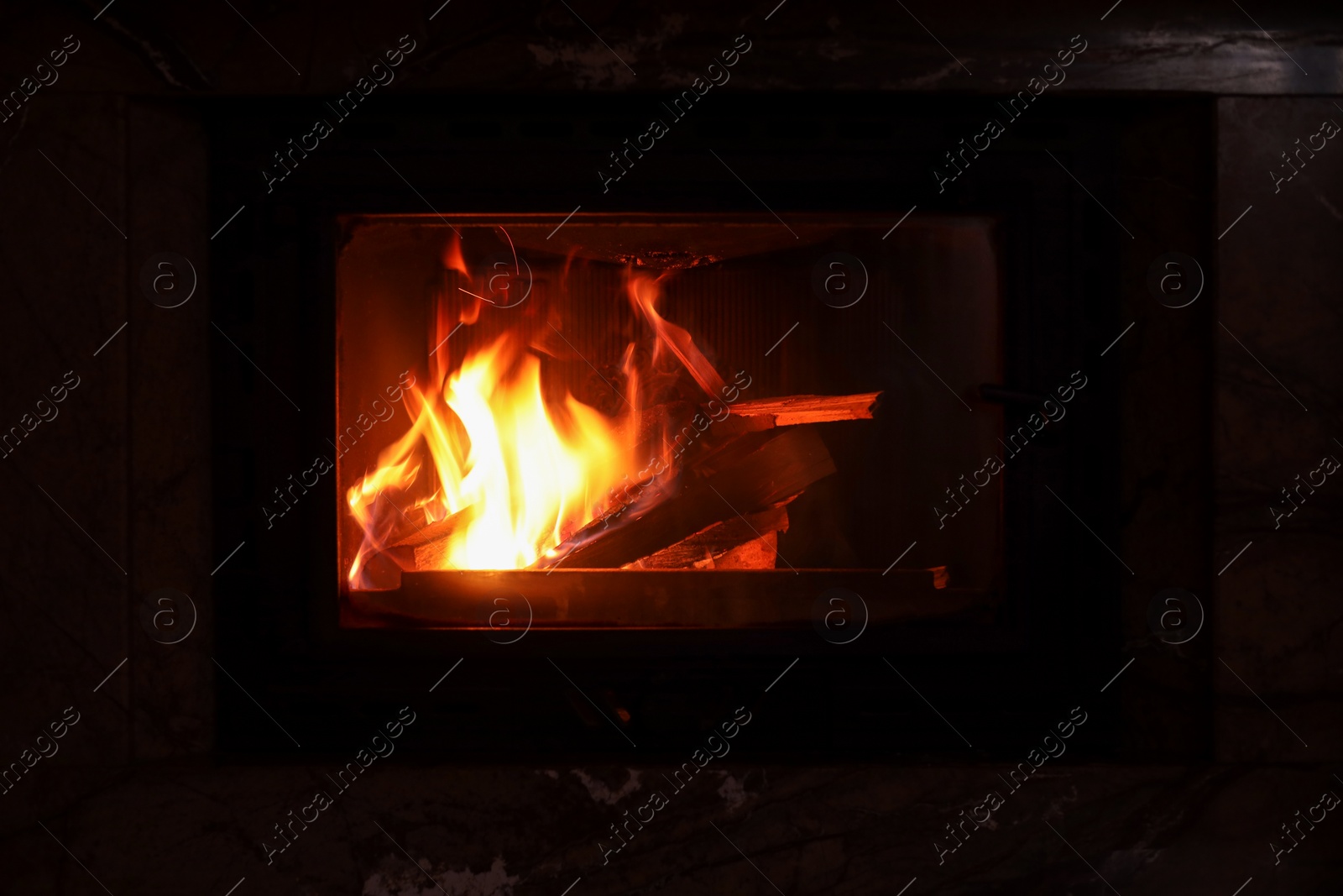 Photo of Fireplace with burning wood in darkness indoors