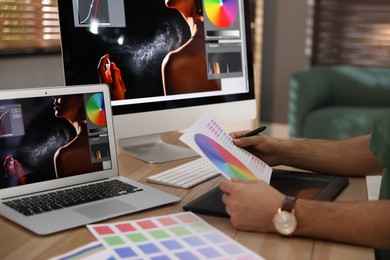 Photo of Professional retoucher working on graphic tablet in office, closeup