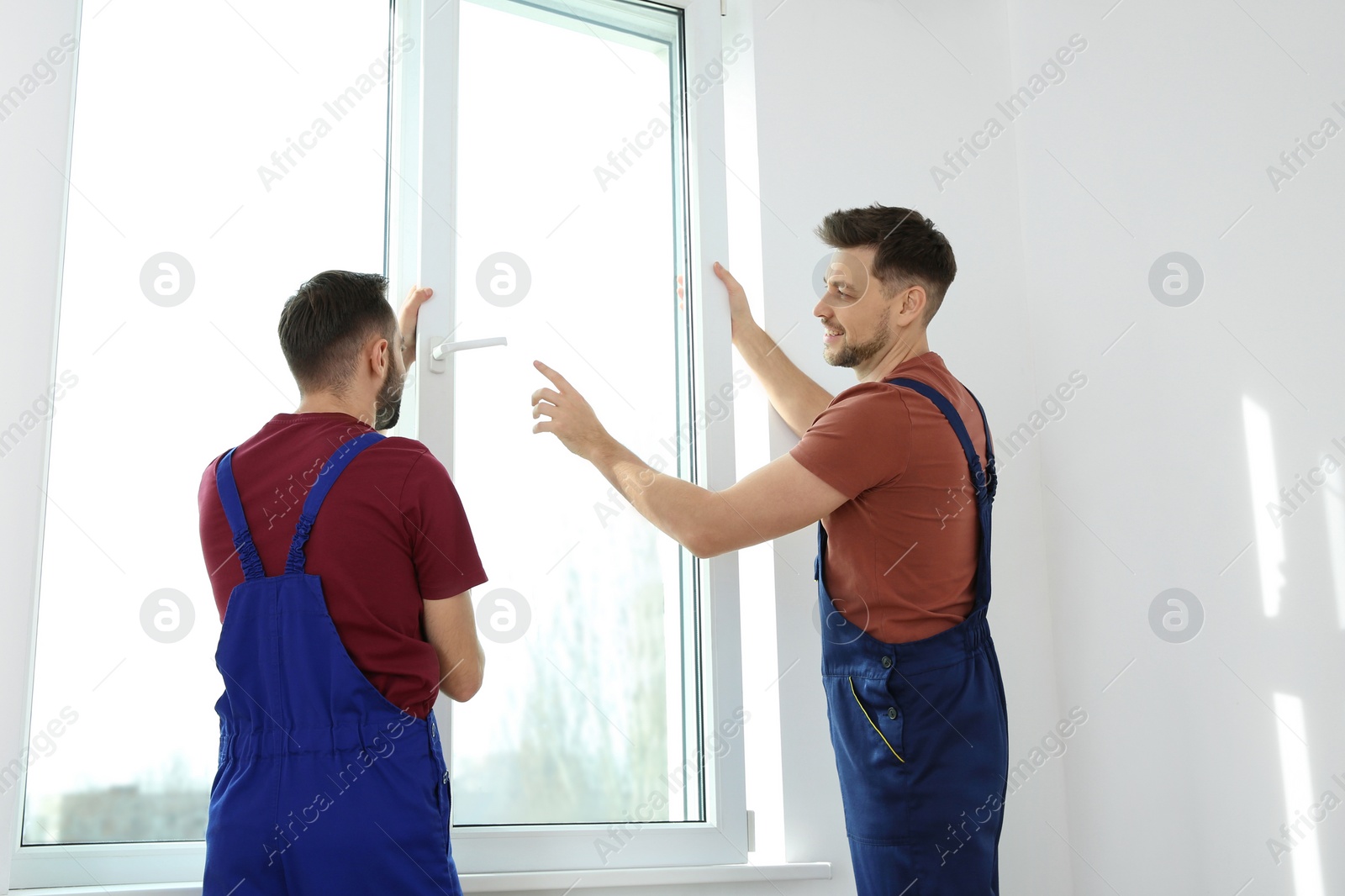 Photo of Construction workers installing plastic window in house