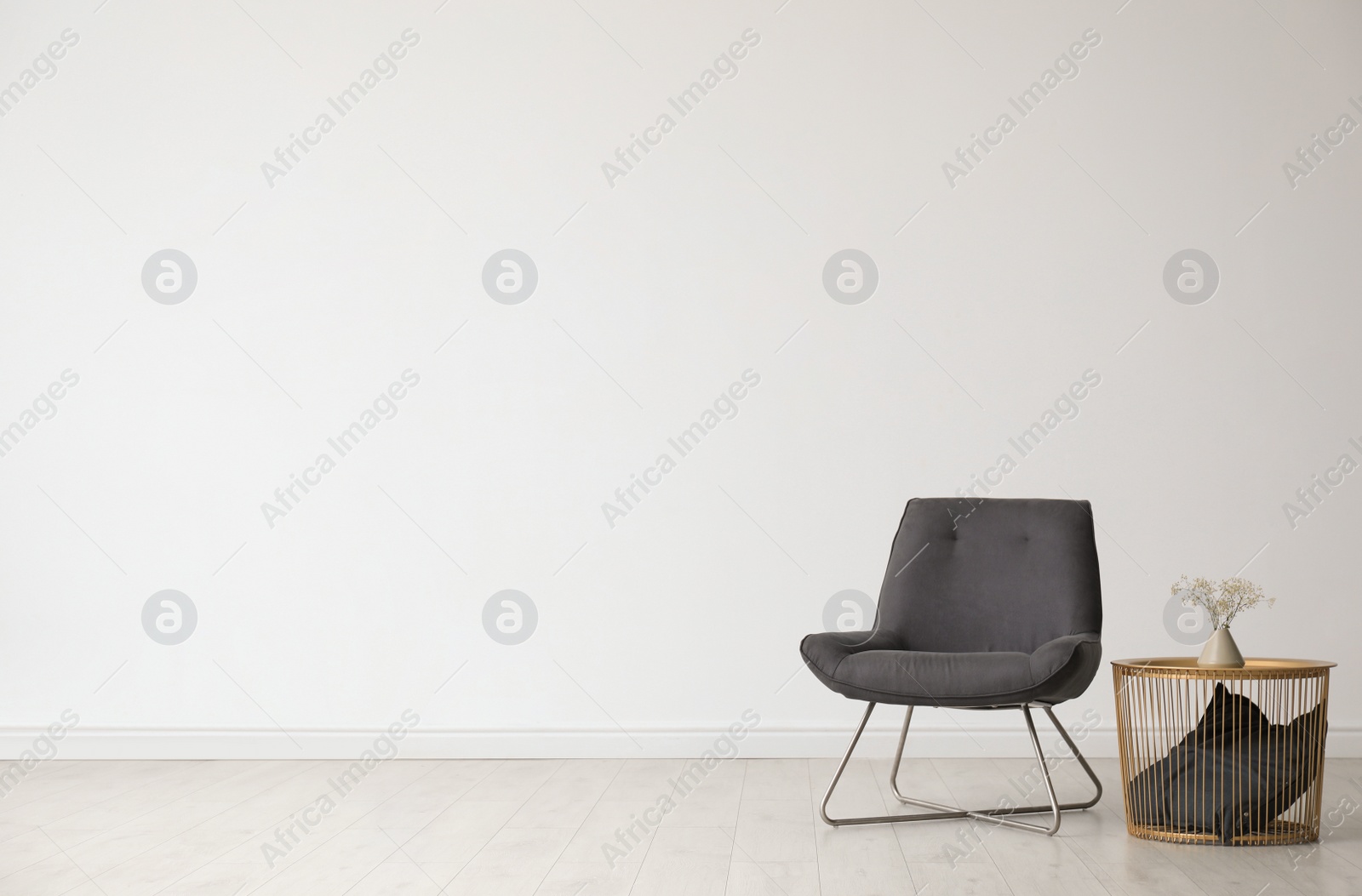 Photo of Stylish living room interior with comfortable chair and side table near white wall. Space for text