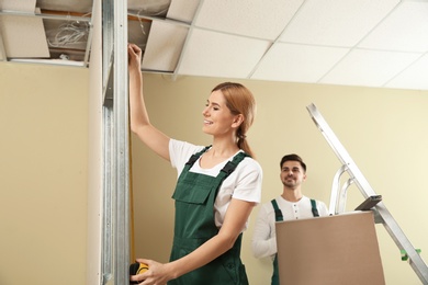 Photo of Workers installing drywall indoors. Home repair service