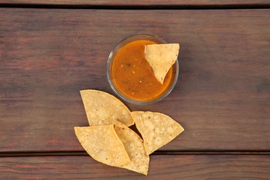 Photo of Tasty salsa sauce and Mexican nacho chips on wooden table, flat lay