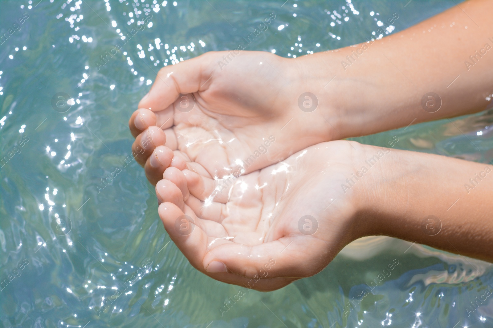 Photo of Kid holding water in hands above sea outdoors, closeup