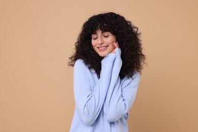 Photo of Happy young woman in stylish light blue sweater on beige background