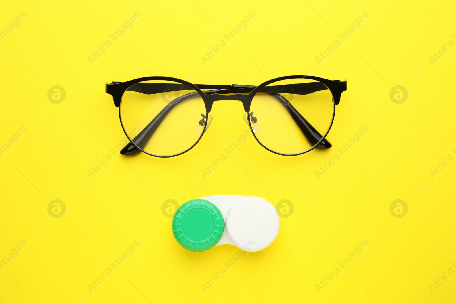 Photo of Case with contact lenses and glasses on yellow background, flat lay