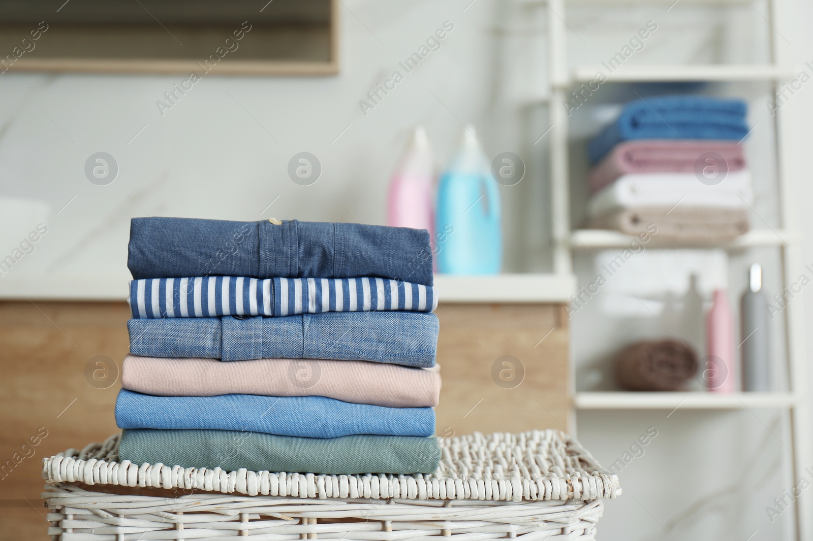 Photo of Stack of fresh laundry on basket in bathroom. Space for text