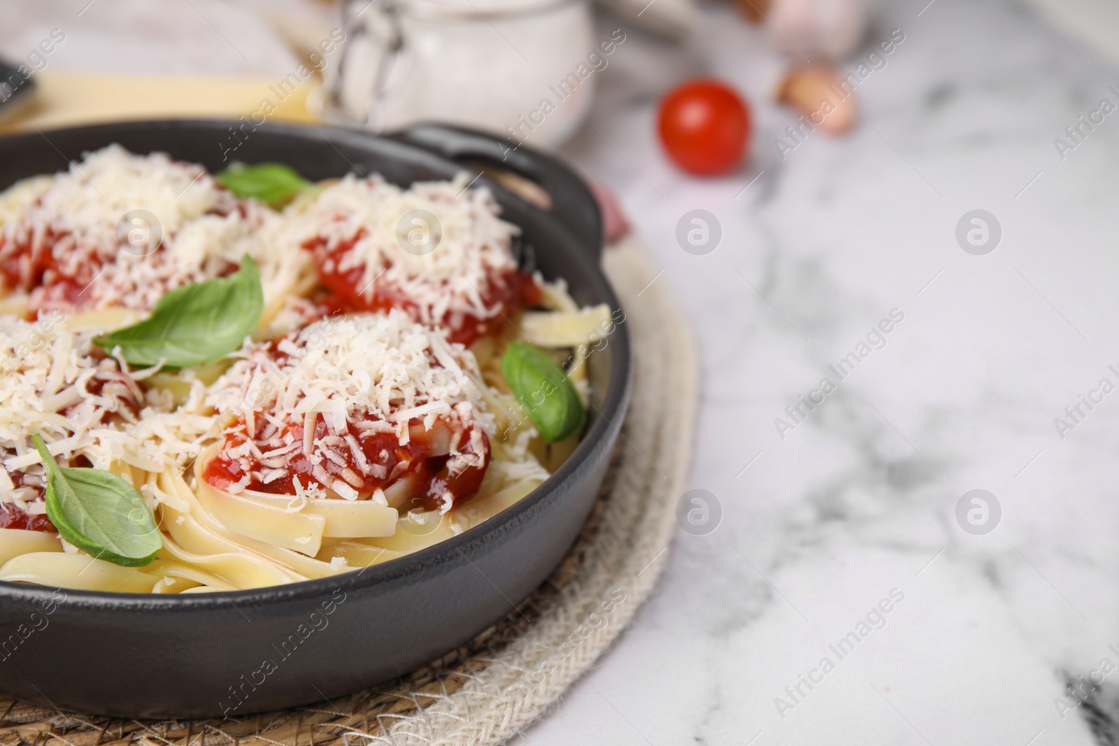 Photo of Delicious pasta with tomato sauce, basil and parmesan cheese on white marble table, closeup. Space for text