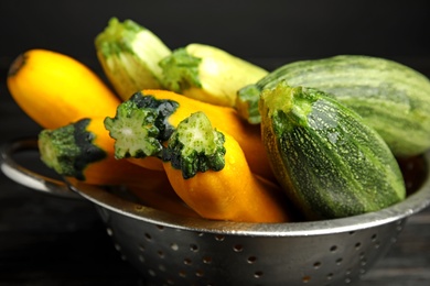 Colander with fresh ripe zucchini on dark background, closeup