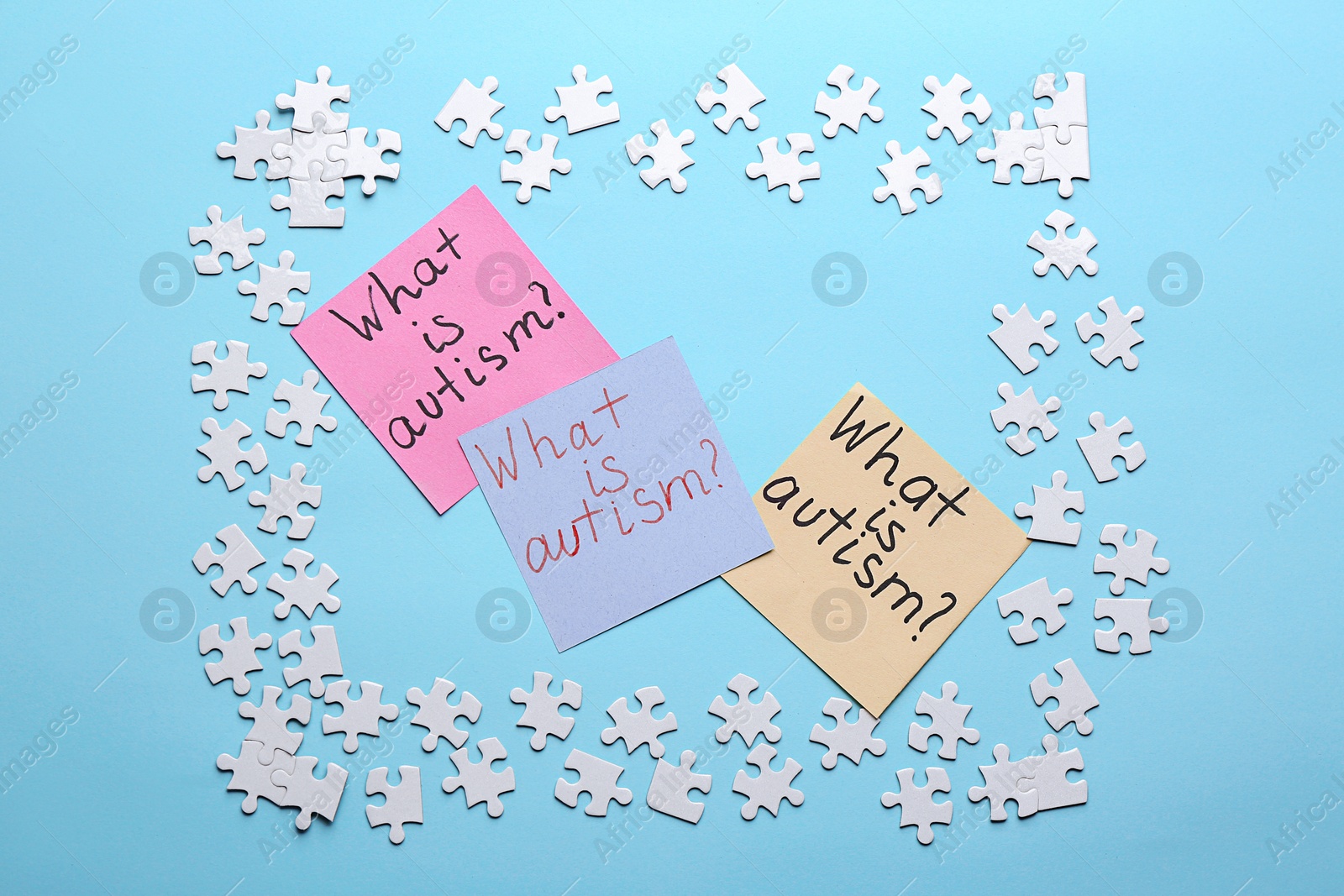 Photo of Sticky notes with phrase "What is autism?" and puzzle pieces on color background