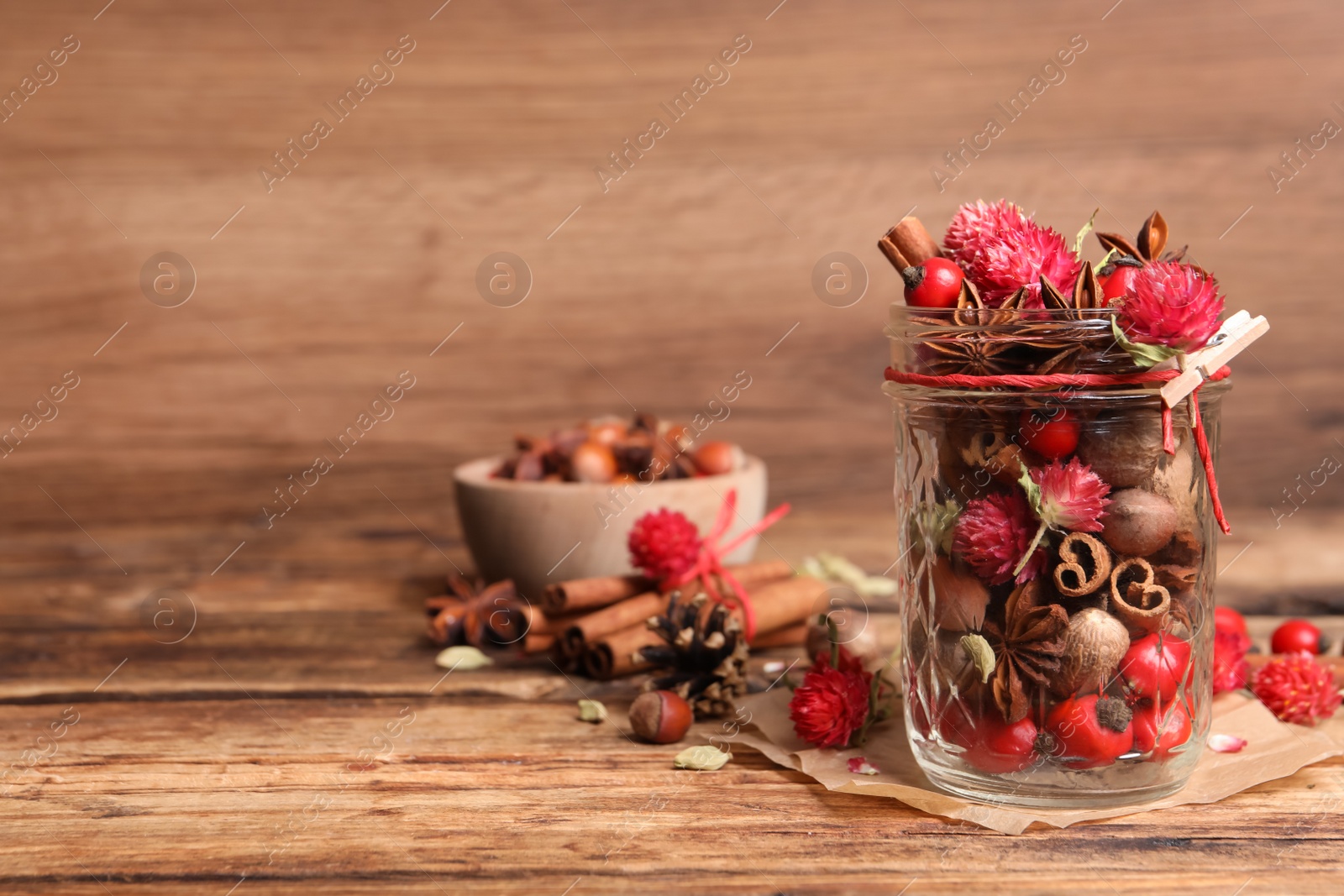 Photo of Aromatic potpourri in glass jar on wooden table. Space for text