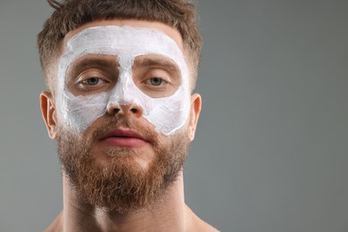 Photo of Handsome man with facial mask on his face against grey background, space for text