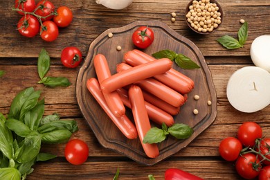 Photo of Fresh raw vegetarian sausages, soybeans and vegetable on wooden table, flat lay