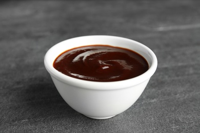 Barbecue sauce in bowl on grey background